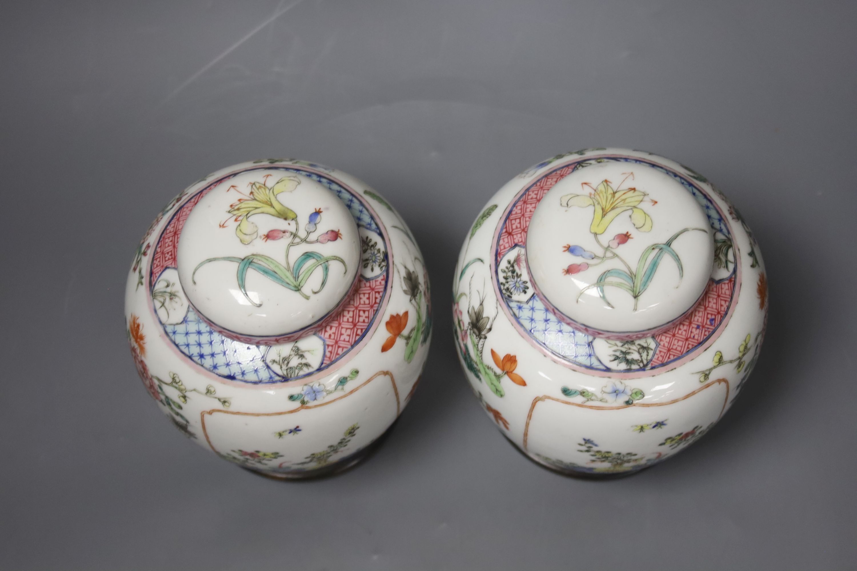 A pair of Chinese famille rose jars and covers, late 19/early 20th century, 15.5cm, on hardwood stands